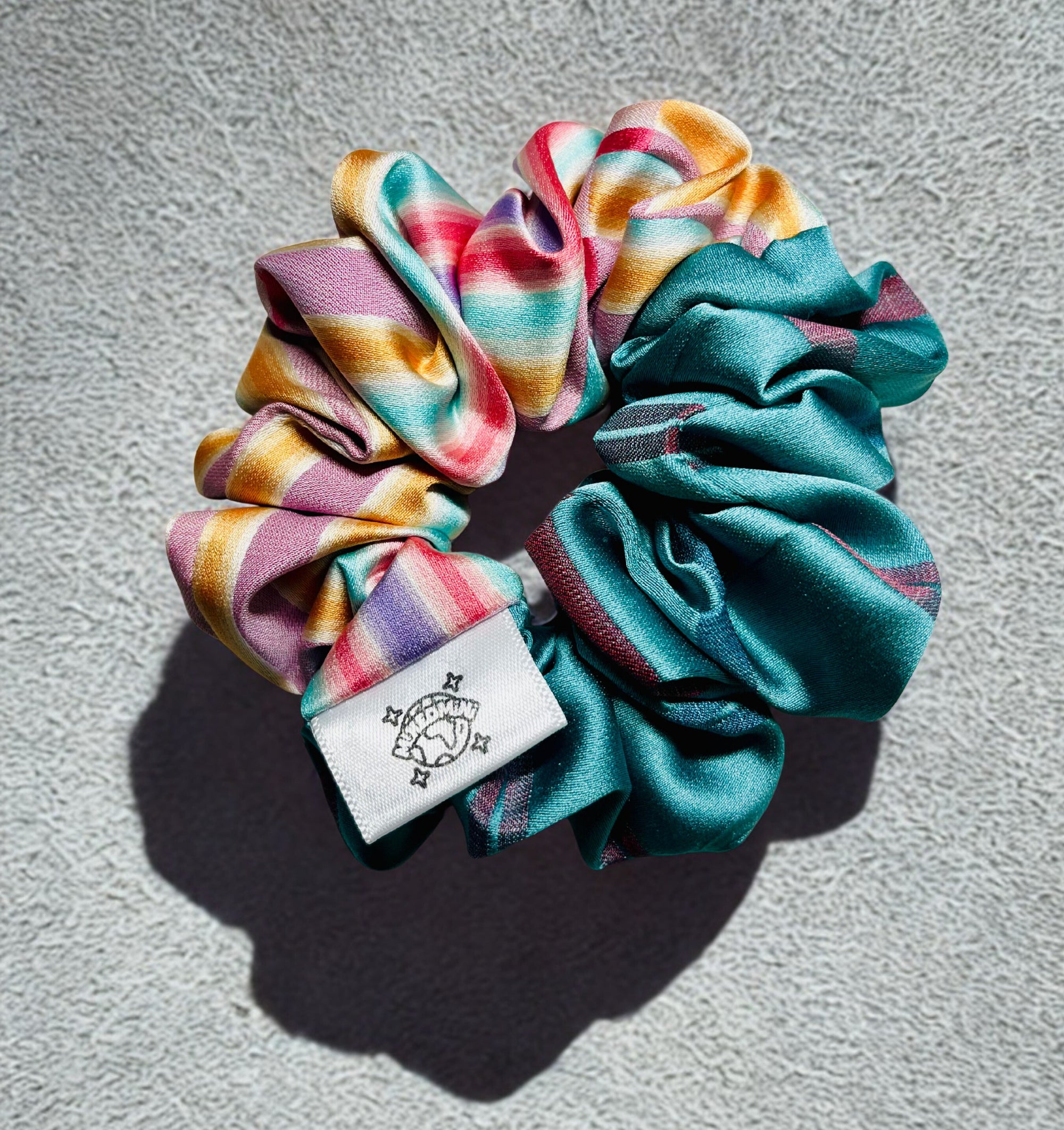 Scrunchie made from upcycled kimono fabric in mixed bright colors with a small logo tag