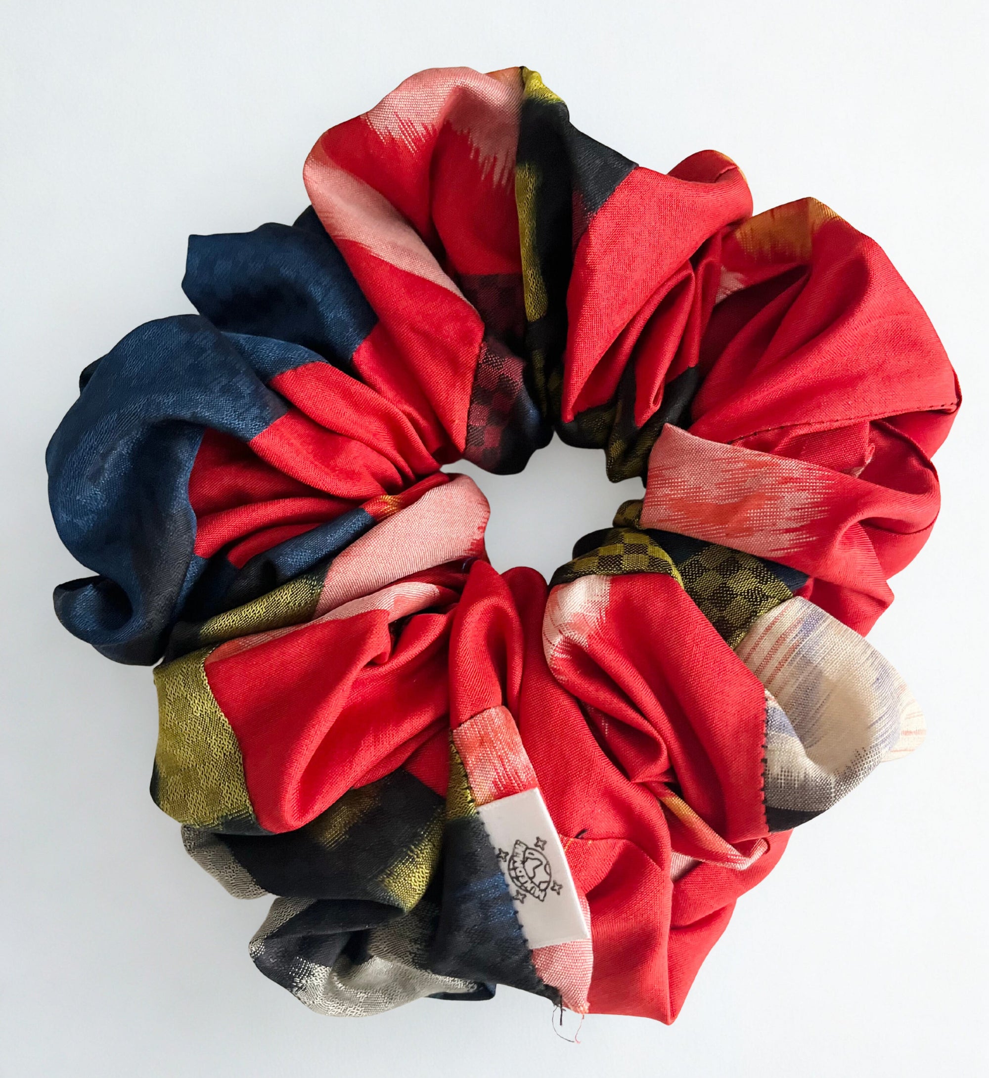 Scrunchie made from upcycled kimono fabric in mixed bright colors with a small logo tag